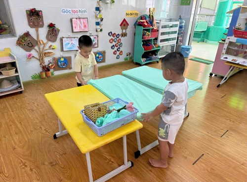 Các bé lớp Mầm 2 tham gia vào việc tổ chức bữa ăn trưa cùng với Cô giáo