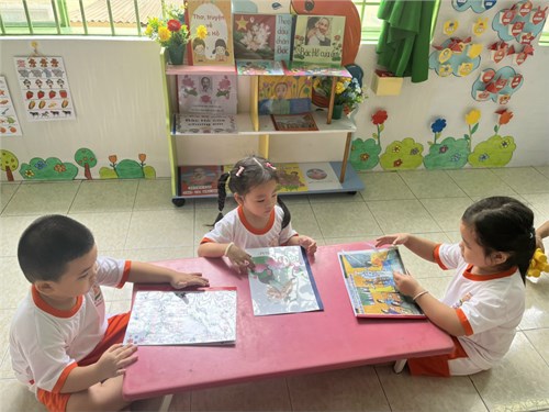 Các bé thực hiện xem sách ảnh về Bác Hồ trong góc Thư viện của lớp