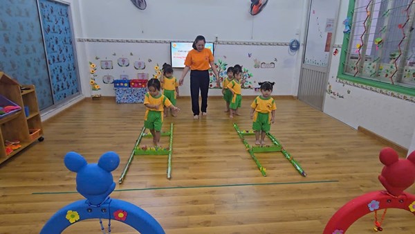 Giáo viên nhóm cơm nát( 19 - 24 tháng tuổi) thực hiện một hoạt động Lĩnh vực phát triển thể chất.