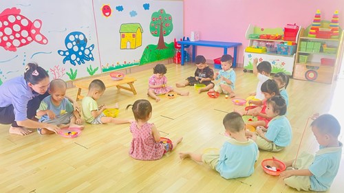 Các bé nhóm cơm thường trong hoạt động xâu dây qua nắp chai