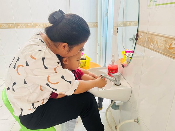 Giáo viên rửa tay cho trẻ nhà trẻ trước khi ăn
